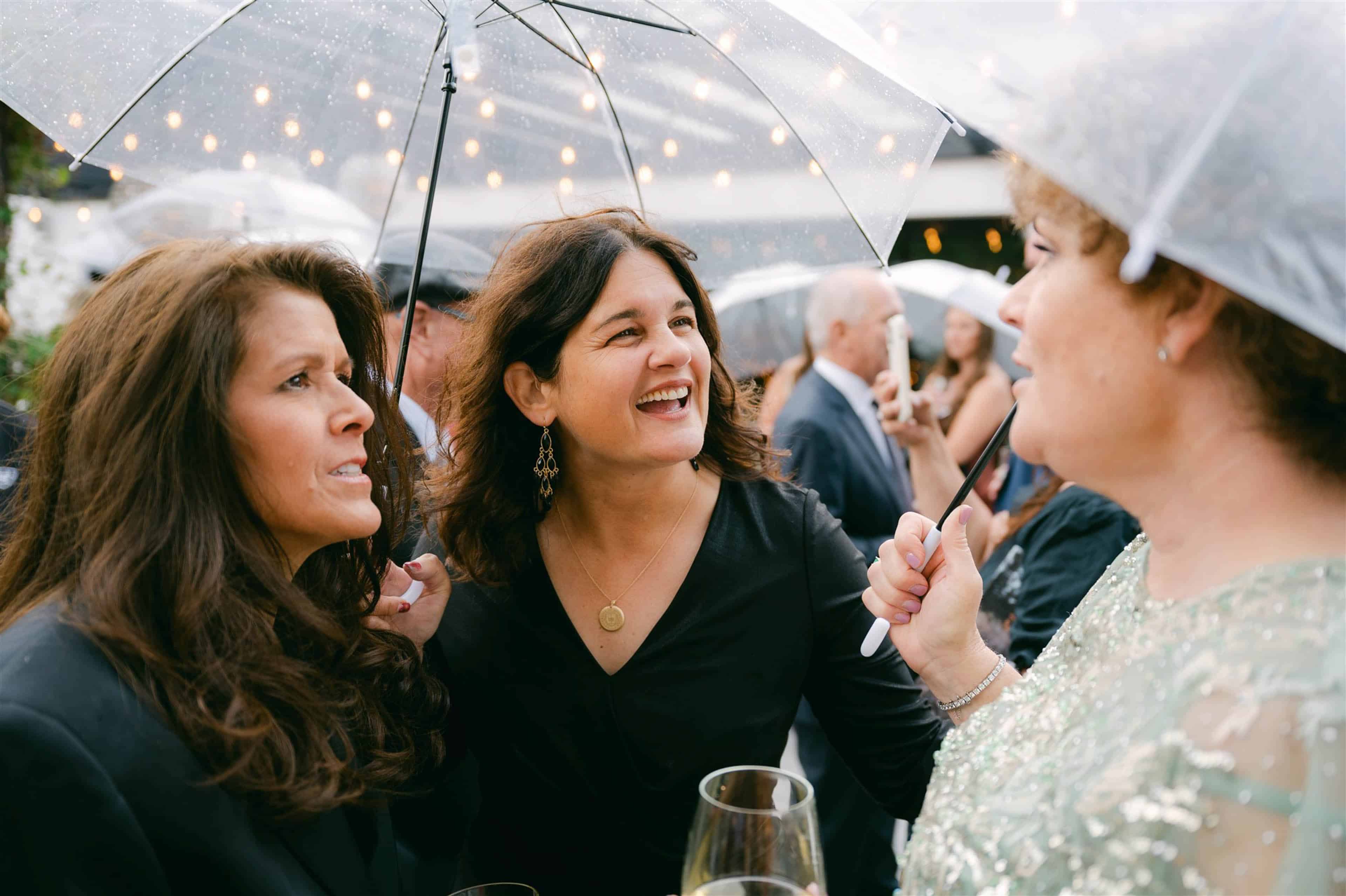 Three women talking to eachother with a clear umbrella over them