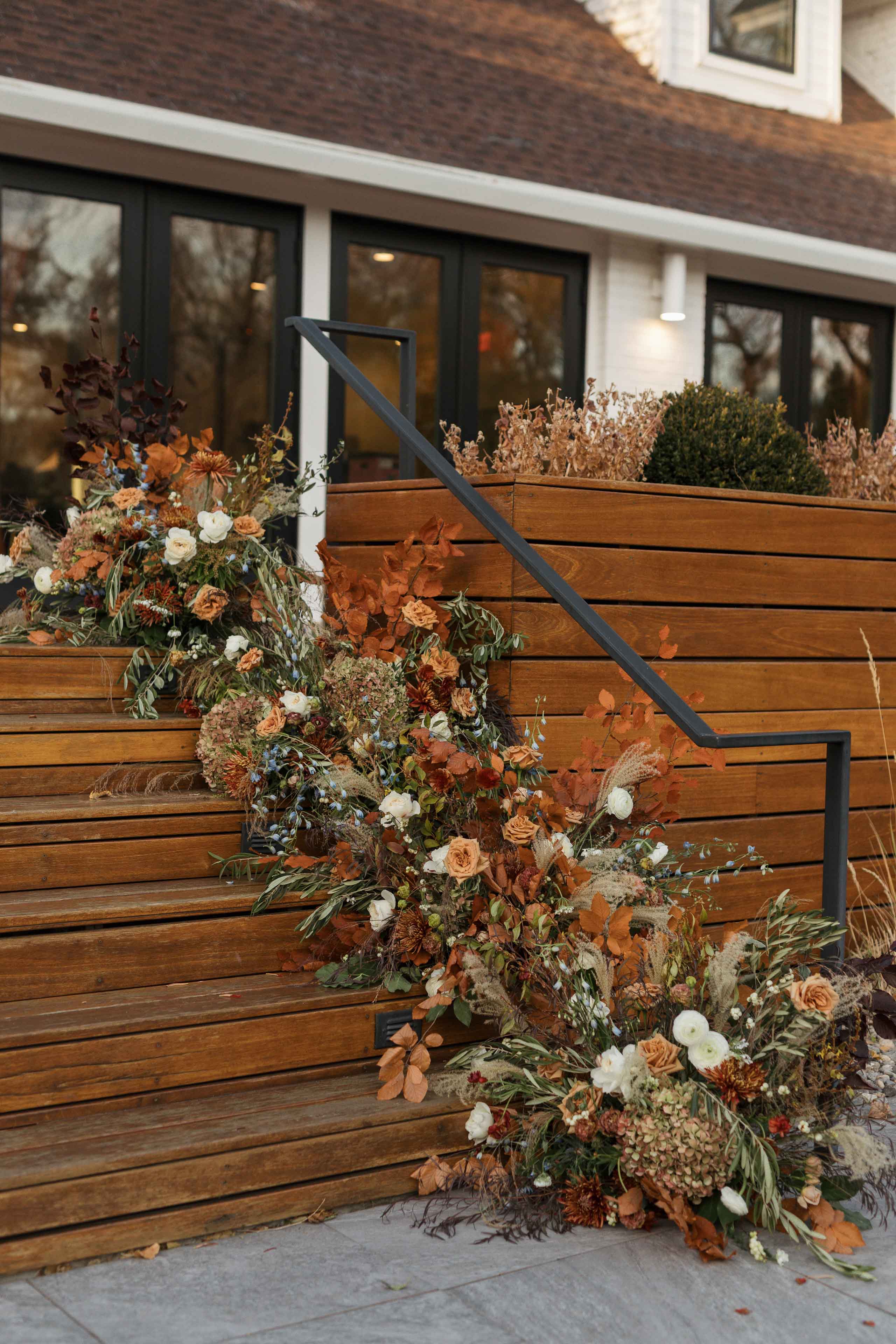 a large fall colored floral arrangement cascading down a set of outdoor stairs