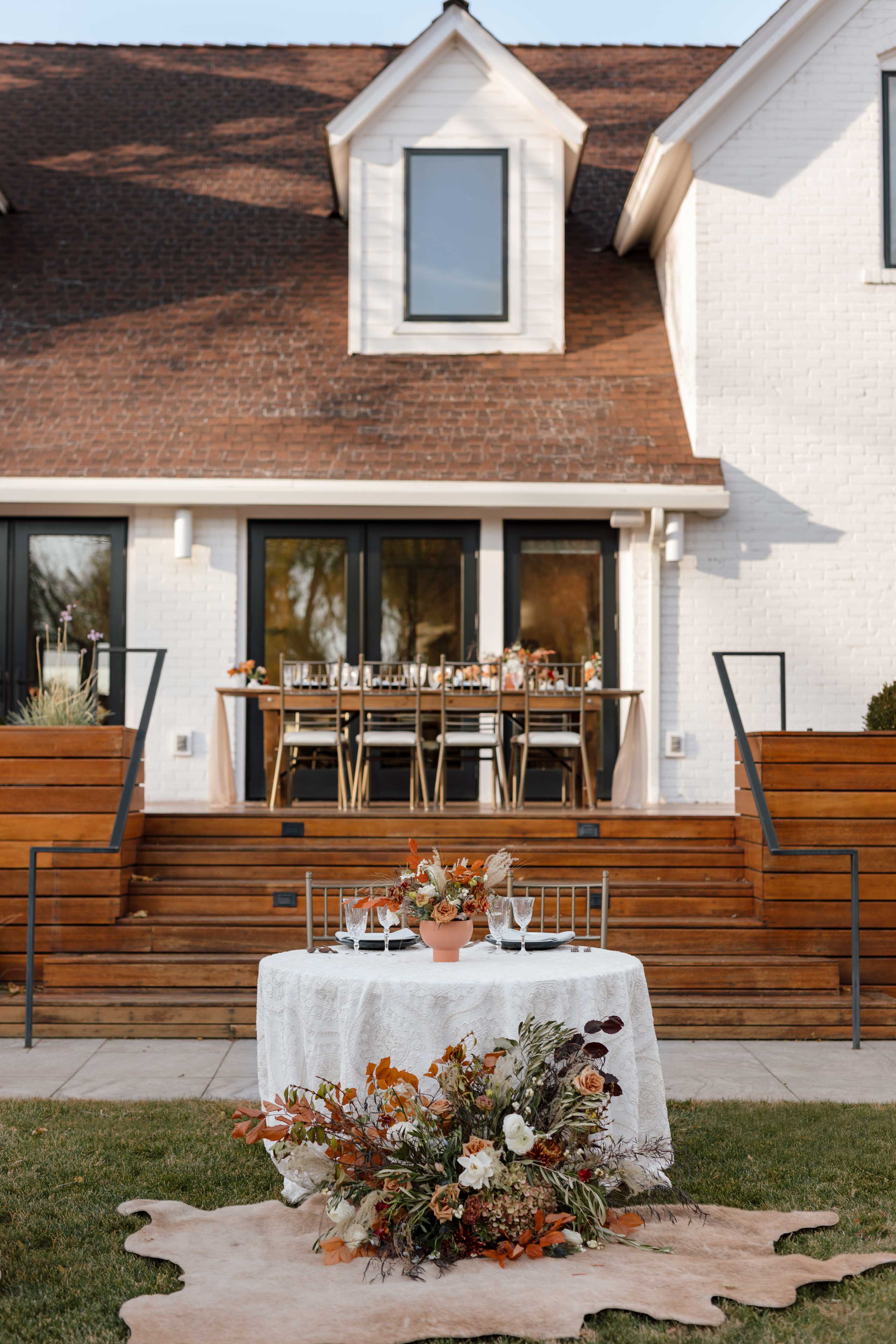 a table decorated with fall flowers in front of the white Elm Estate building