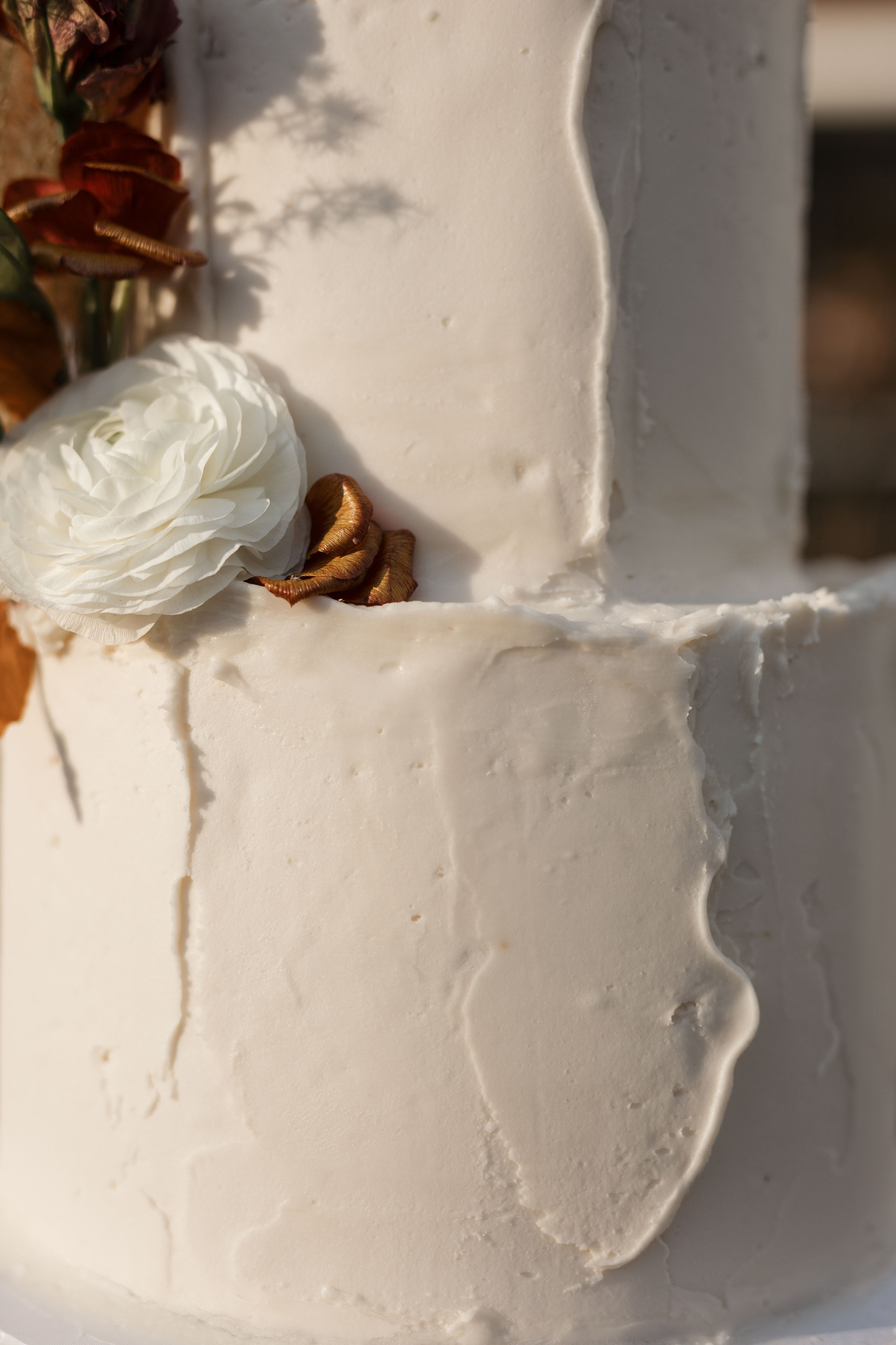a wedding cake with textured frosting and fall colored flowers 1