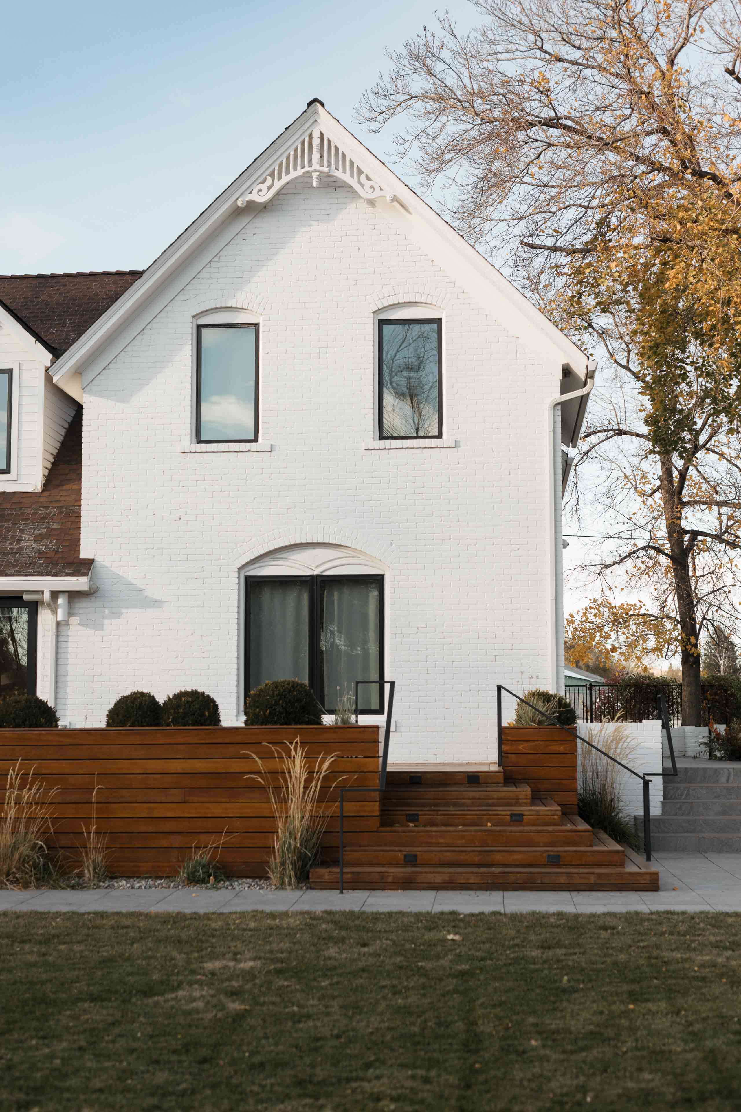 a white building with a wood deck green grass and blue skies 1