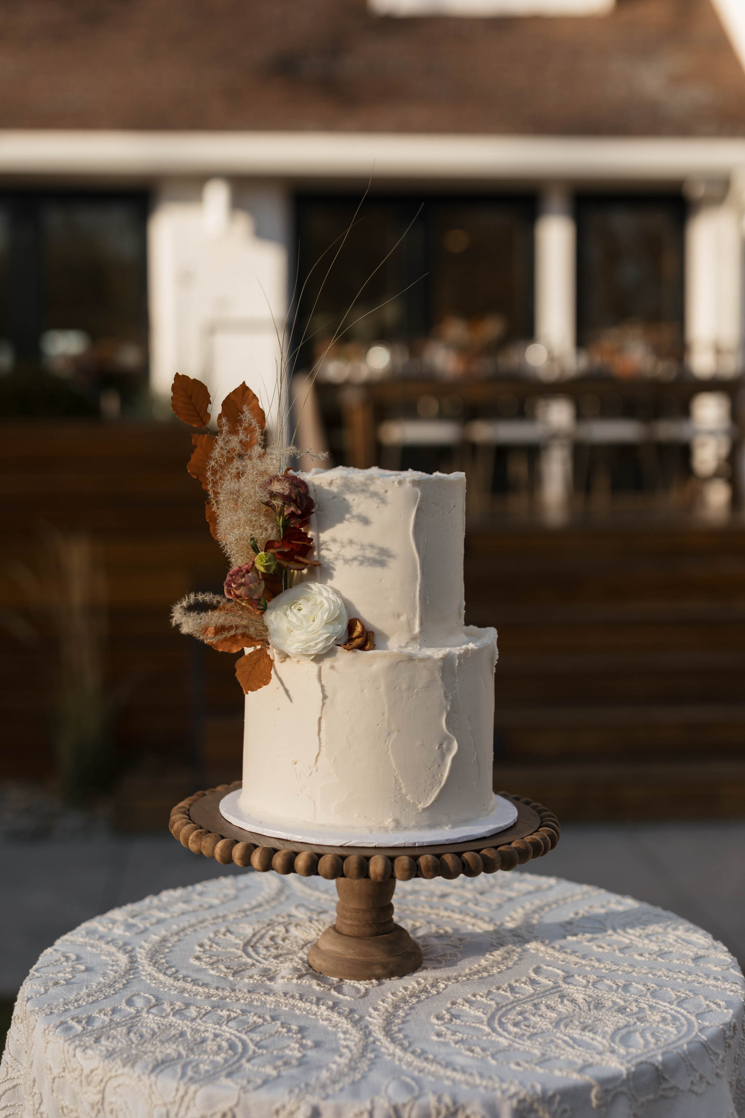 a white wedding cake with fall colored florals on top 1