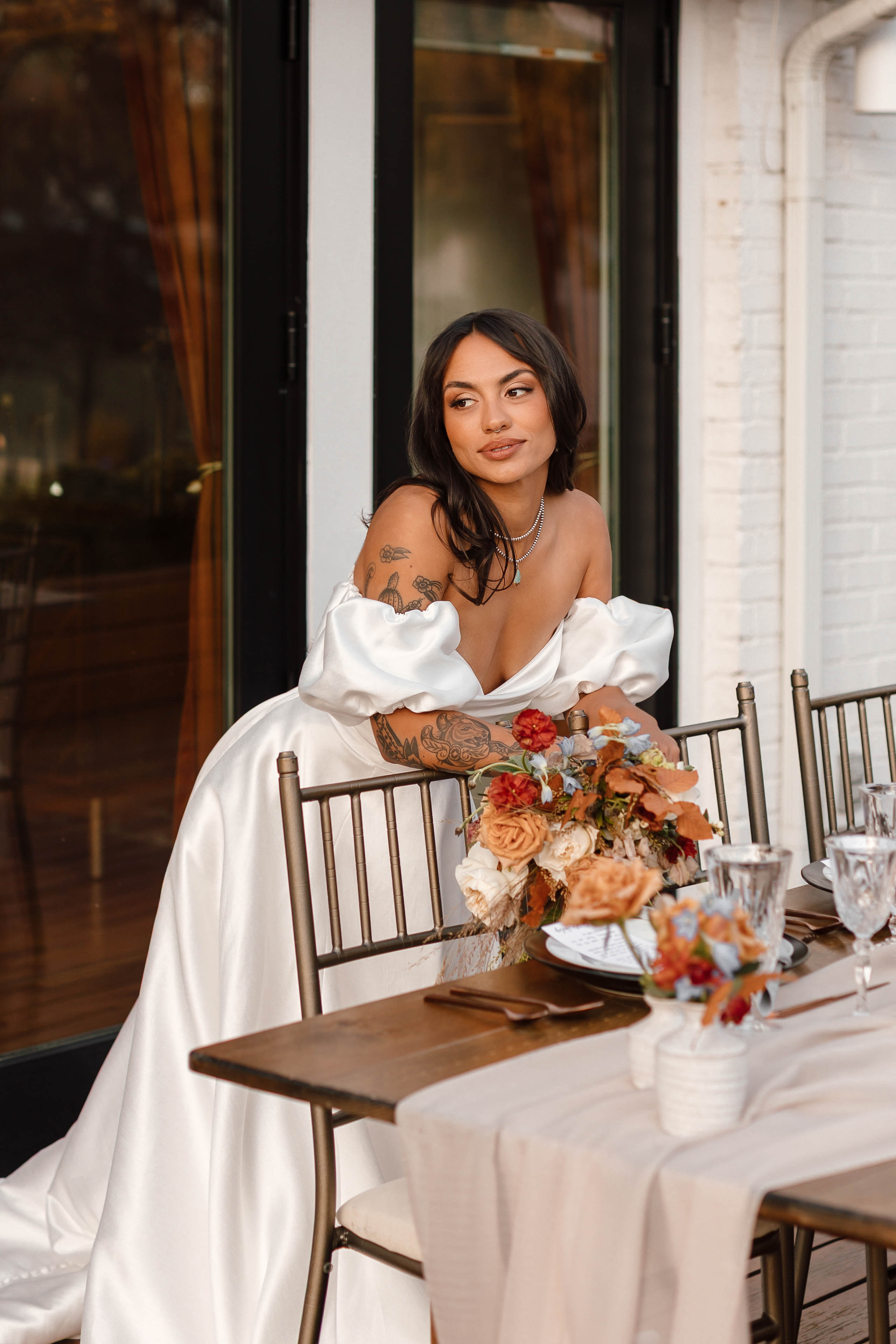 a woman standing by tables and chairs decorated with linen and fall colored flowers